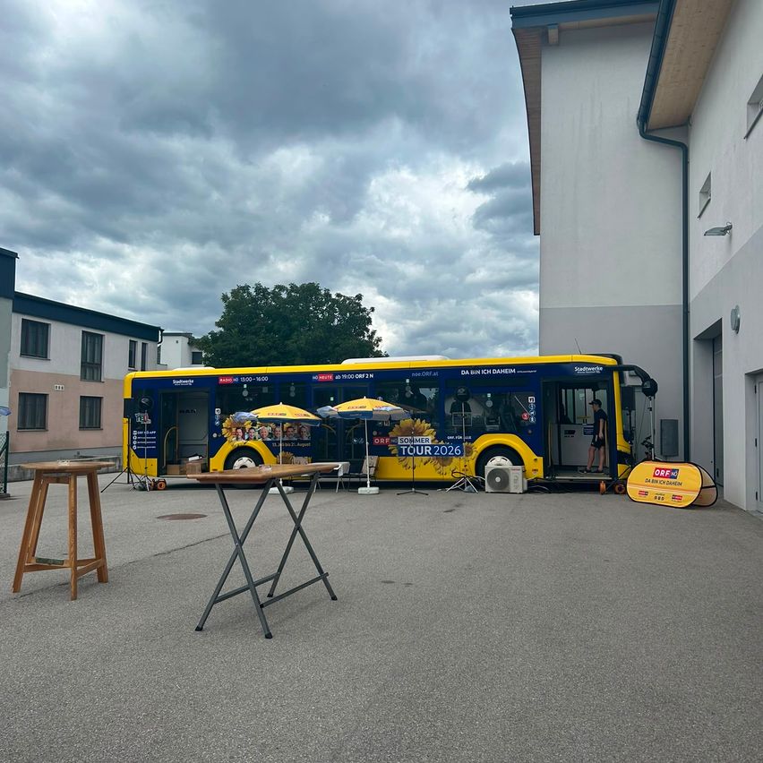 ORF Sommer Tour 2026 Bus mit Sonnenschirmen und Tischen vor einem Gebäude