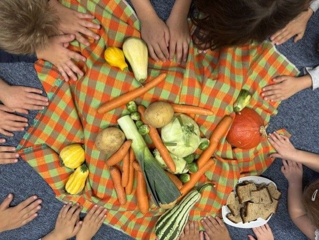 Eine Gruppe von Kindern versammelt sich um einen Tisch mit verschiedenen Gemüsesorten.