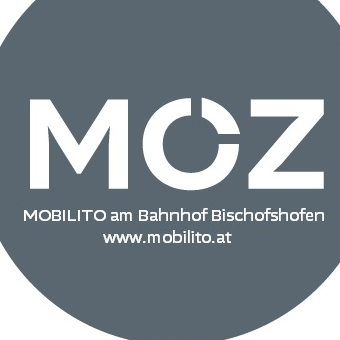 Ein kreisförmiges Logo für MOBILITO am Bahnhof Bischofshofen. Das Logo zeigt den Text 'MOZ' in Weiß auf grauem Hintergrund. Darunter befindet sich die Website-Adresse 'www.mobilito.at.'