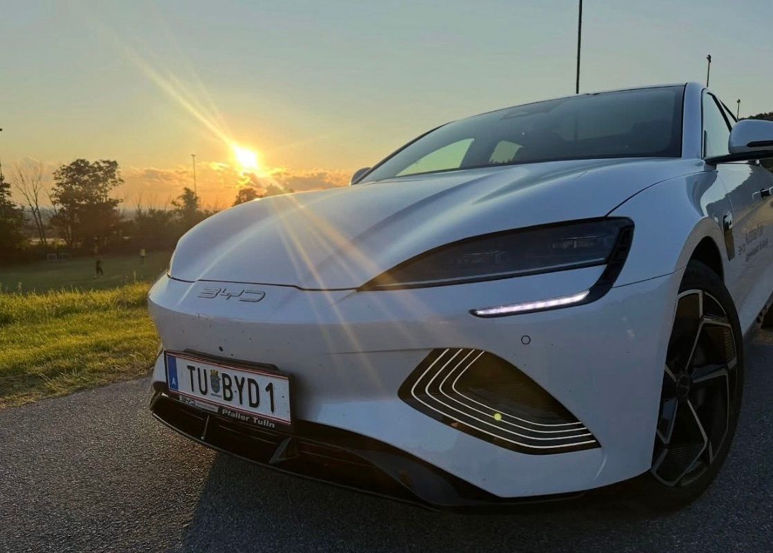 Die Front eines weißen Sportwagens mit dem Kennzeichen TU-BYD 1 ist auf einer Straße geparkt, während die Sonne hinter ihm untergeht.