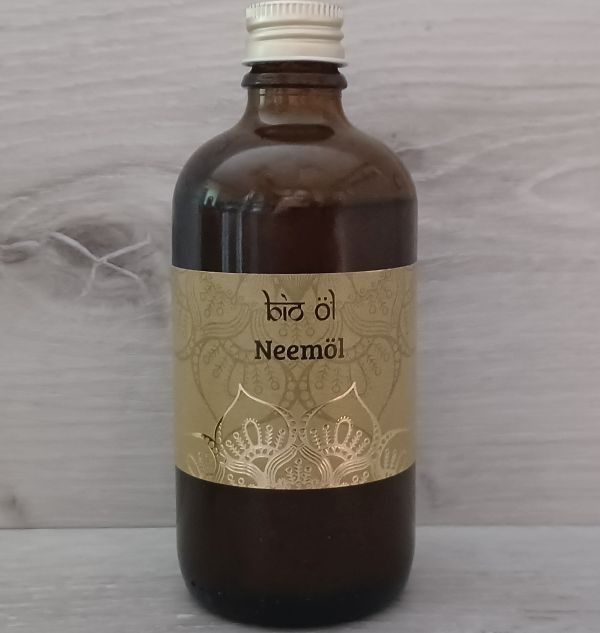 Eine Flasche Neemöl, eine dunkle braune Flüssigkeit mit einem weißen Verschluss, steht auf einer Marmoroberfläche.