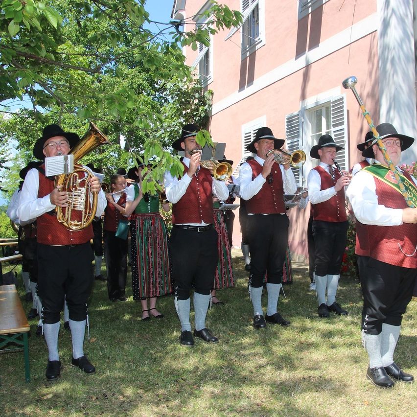 Musikkapelle spielt in Tracht vor rosa Gebäude in Österreich