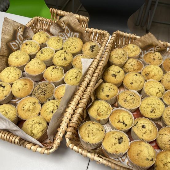 Zwei Weidenkörbe voller Muffins, einige mit dunklen Flecken, auf einer weißen Oberfläche platziert.