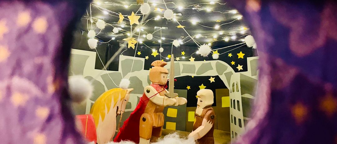 Eine Weihnachtsdekoration mit einem Ritter und einem Pferd in einem lila Tunnel mit Sterndekorationen und Lichtern.