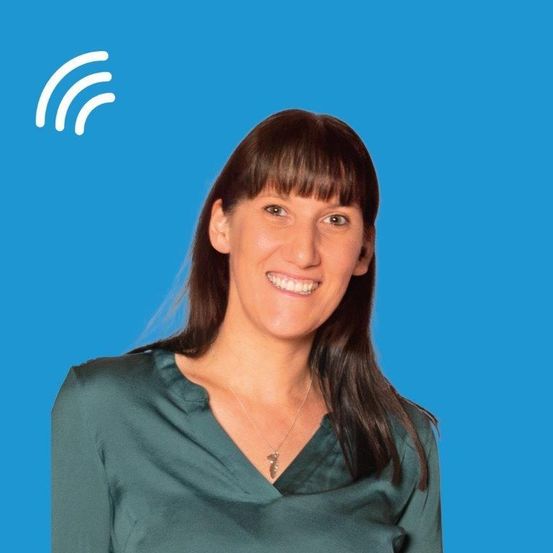 Eine lächelnde Frau mit Pony und einer Halskette steht vor einem blauen Hintergrund mit einem weißen Signalsymbol.