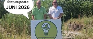 Zwei Männer stehen neben einem Schild mit einer Bild einer Glühbirne. Einer trägt ein grünes Shirt, der andere ein weißes Shirt mit Text. Eine Sprechblase sagt 'Update 2026.'