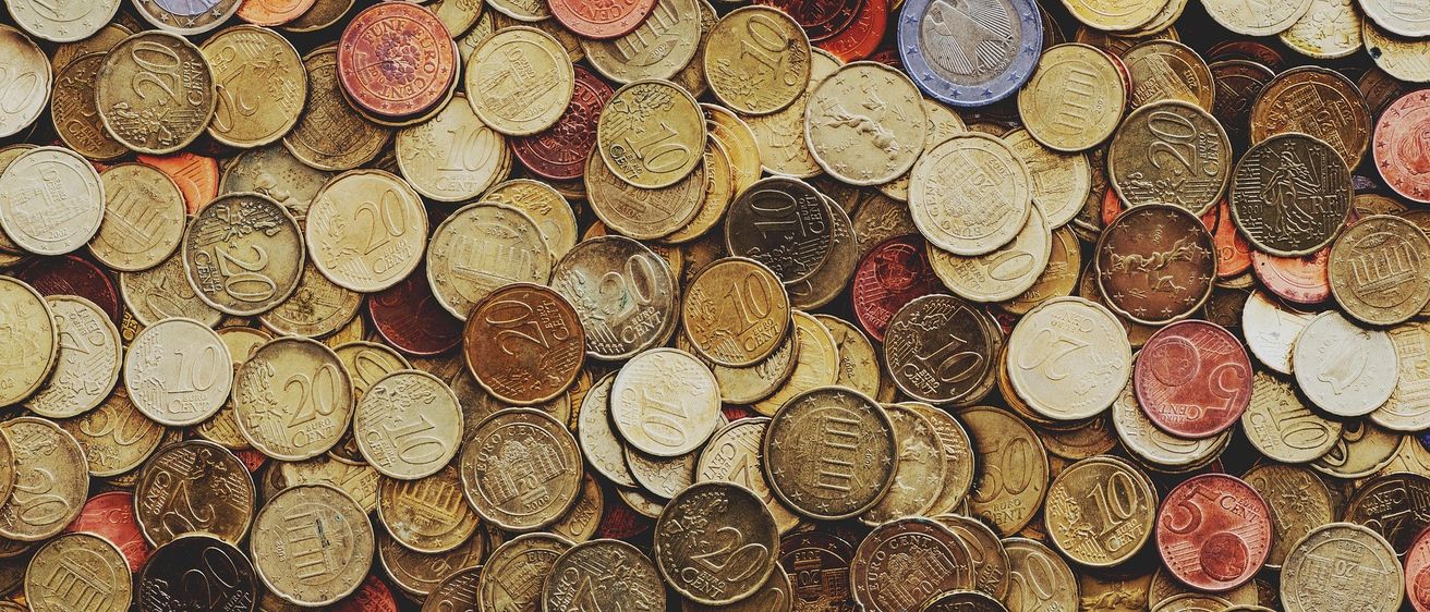 Ein Haufen Münzen in verschiedenen Farben und Nennwerten, auf einer Oberfläche verteilt. Die Münzen reichen von 1 Cent bis 50 Cent.