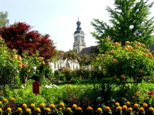 Ein Garten mit leuchtenden Blumen und einem hohen Turm im Hintergrund.