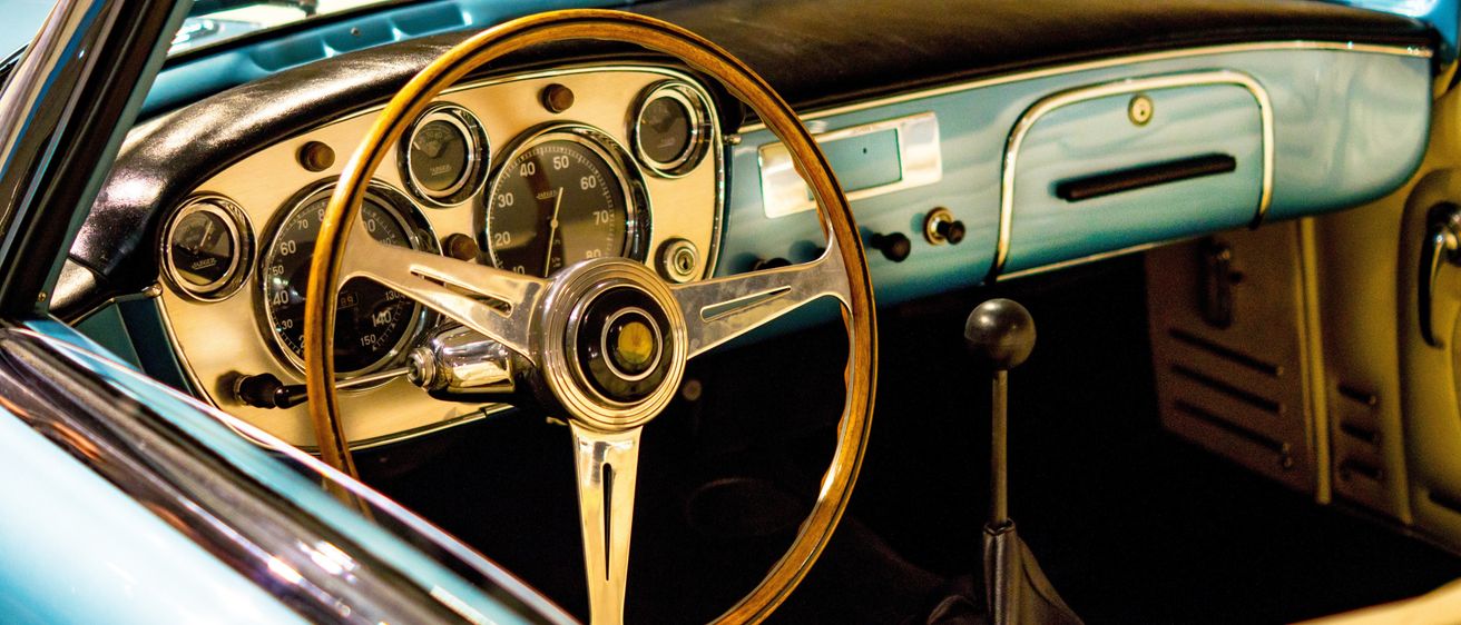 Das Vintage-Auto-Interieur mit goldenem Lenkrad und Anzeigen, beleuchtet mit blauen Lichtern.
