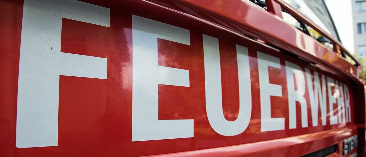 Eine Nahaufnahme des Wortes Feuer, das in Weiß auf rotem Hintergrund geschrieben ist. Es handelt sich wahrscheinlich um einen Teil eines Feuerwehrwagens.
