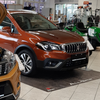 Zwei Autos sind in einem Showroom geparkt. Das vordere Auto hat seine Motorhaube geöffnet und den Motor offenliegend. Das zweite Auto ist orange mit geschlossener Motorhaube.