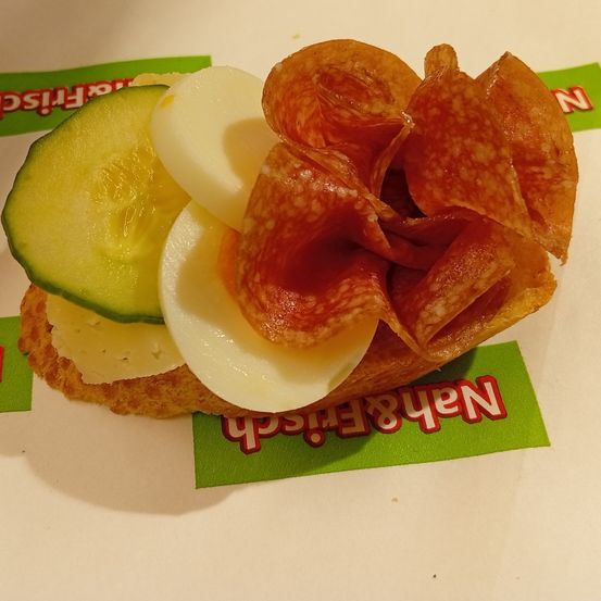 Ein Sandwich mit Gurke, Käse und Salami auf einem weißen Teller, gekennzeichnet mit dem Wort 'Nerve'.