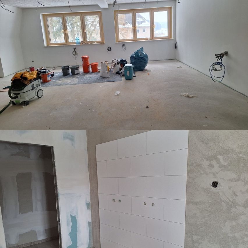 Ein Raum in Renovierung, mit einem grauen Boden, weißen Wänden und mehreren Eimern. Der obere Teil des Bildes zeigt einen Raum mit einem grauen Boden und einer weißen Wand.