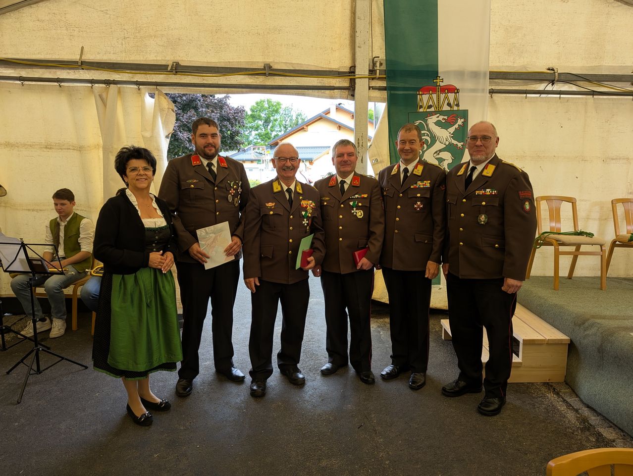 Fünf Personen, darunter eine Frau, in Uniformen stehen zusammen, wahrscheinlich für ein Gruppenfoto. Sie stehen in einem Zelt.