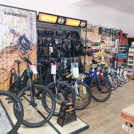 Ein Fahrradgeschäft mit einer Ausstellung verschiedener Fahrräder, Helme und Zubehör. Ein Poster eines Fahrers auf einem Mountainbike ist an der Wand.
