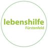 Das Bild zeigt ein Logo für 'lebenshilfe Fürstenfeld', das auf einem weißen Hintergrund mit einem grünen kreisförmigen Rand dargestellt ist.
