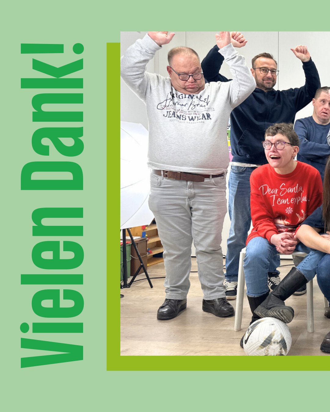 A group of adults are gathered in a room with a soccer ball, some are laughing and posing for a photo.