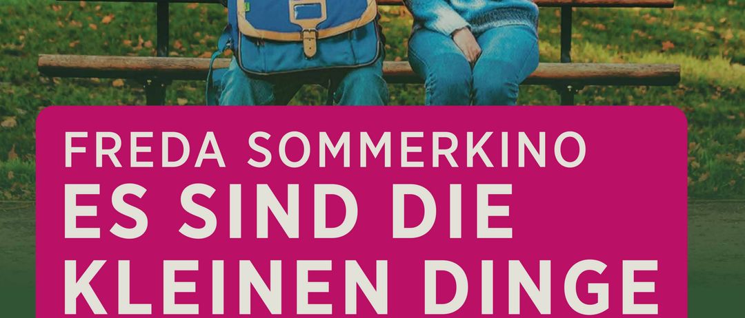 Ein älterer Mann und eine Frau sitzen auf einer Parkbank und halten Händchen. Der Mann trägt eine Brille und einen Rucksack. Die Frau trägt einen blauen Pullover. Ein rosa Banner mit weißem Text lautet 'Freda Sommerkino Es sind die kleinen Dinge'.