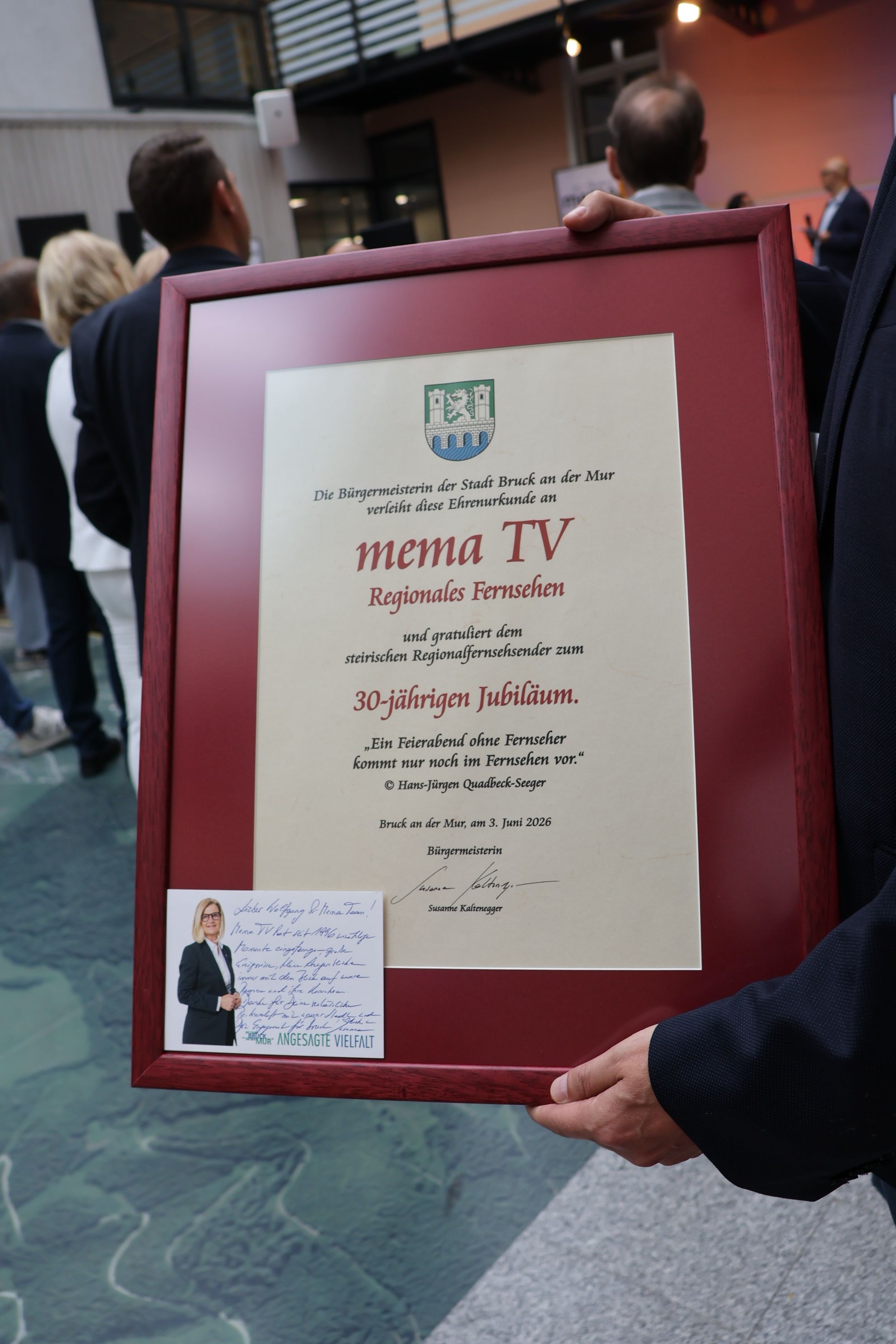 Ein gerahmtes Zertifikat mit rotem Rand, betitelt 'Regionalfernsehen' und feiert 30 Jahre. Es erwähnt einen steirischen Regionalfernsehsender. Eine kleine Karte ist angehängt.
