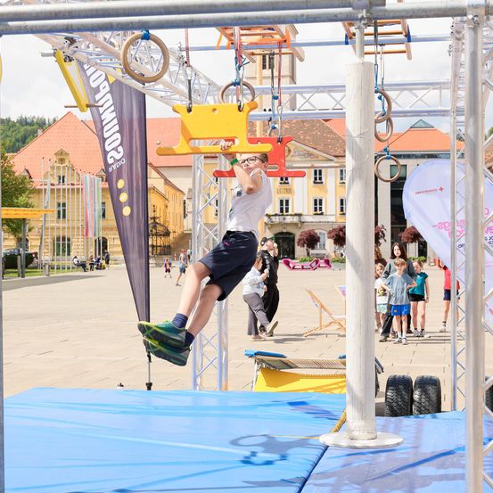 Ein junger Junge springt auf einem Reifenschaukel, während er einen Hindernisparcours auf einem Freiluftplatz absolviert.