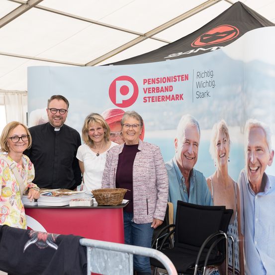 Eine Gruppe von Menschen steht vor einem Stand mit einem Banner, auf dem 'Pensionisten Verband Steiermark' steht. Zwei Frauen und zwei Männer lächeln für die Kamera.