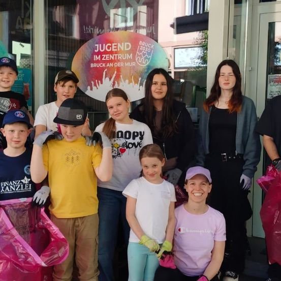 Eine Gruppe von Kindern und Erwachsenen steht vor einem Gebäude mit dem Schild Jugend im Zentrum, einige halten Plastiktüten in den Händen.