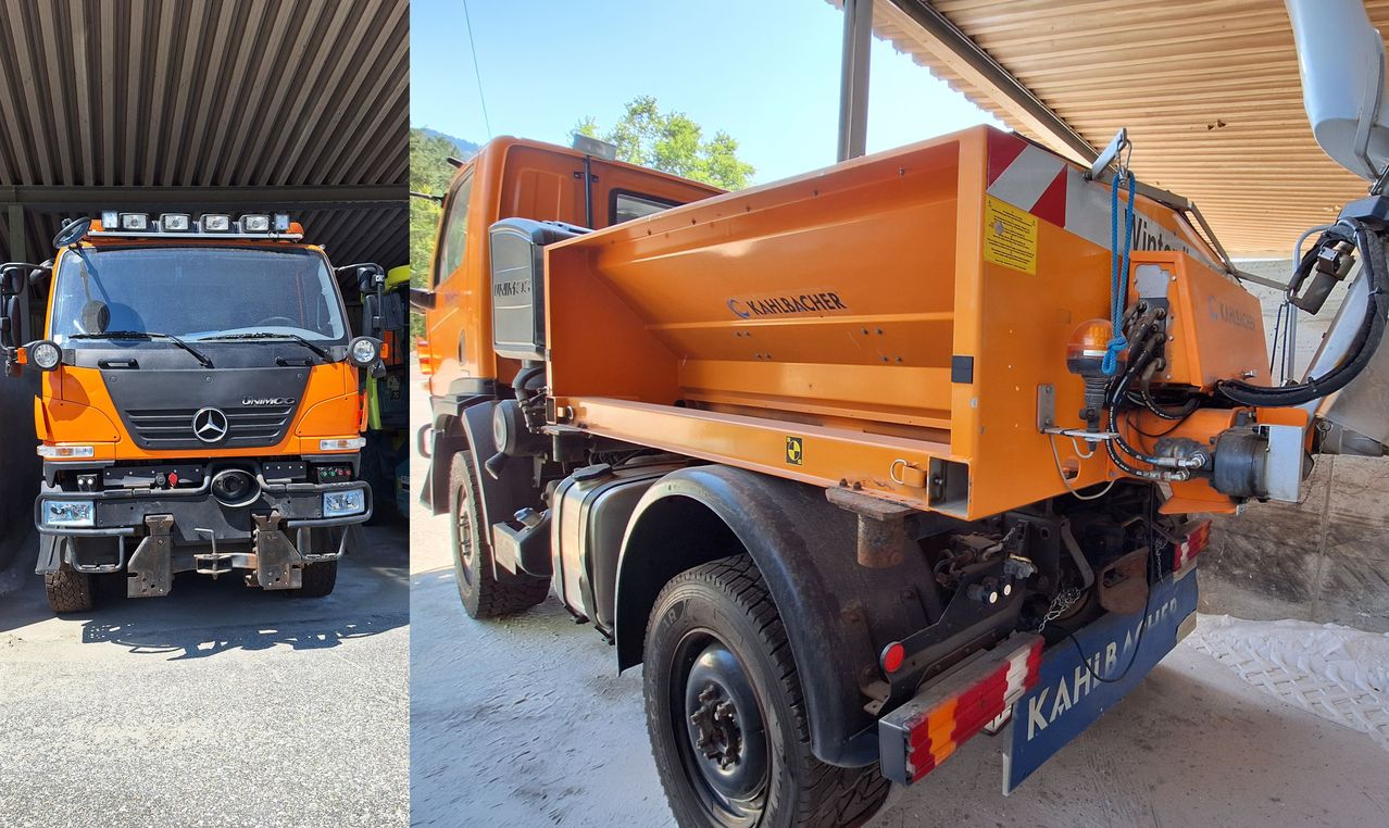 Ein orangefarbener Kipplaster steht unter einem Schutzdach bei klarem Himmel. Der Lastwagen hat einen großen orangefarbenen Körper und einen schwarzen Stoßfänger.