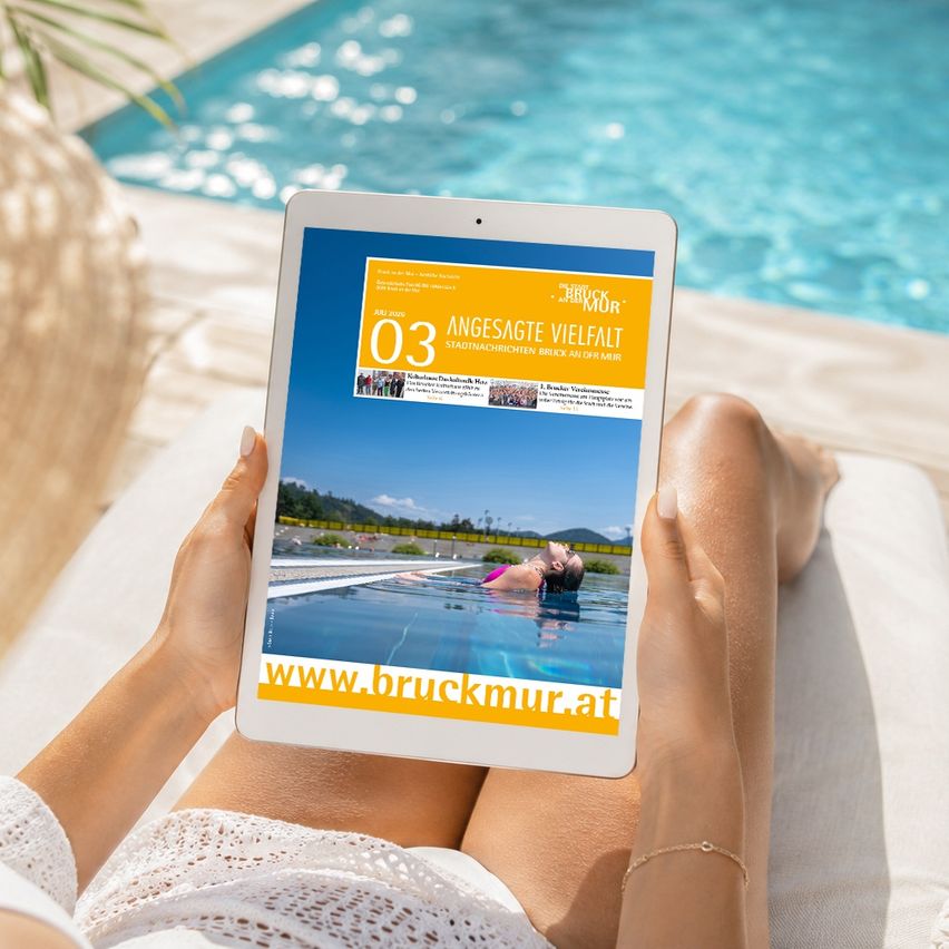 A person holds a tablet displaying a magazine cover with an image of a woman swimming in a pool. The tablet screen shows the magazine title 'ANGEBOT' and a website address.