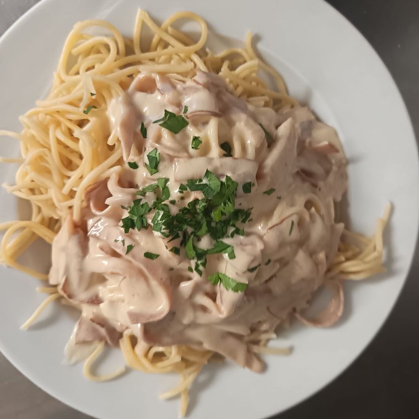 A plate of creamy mushroom spaghetti topped with fresh parsley. The creamy sauce covers the pasta evenly.