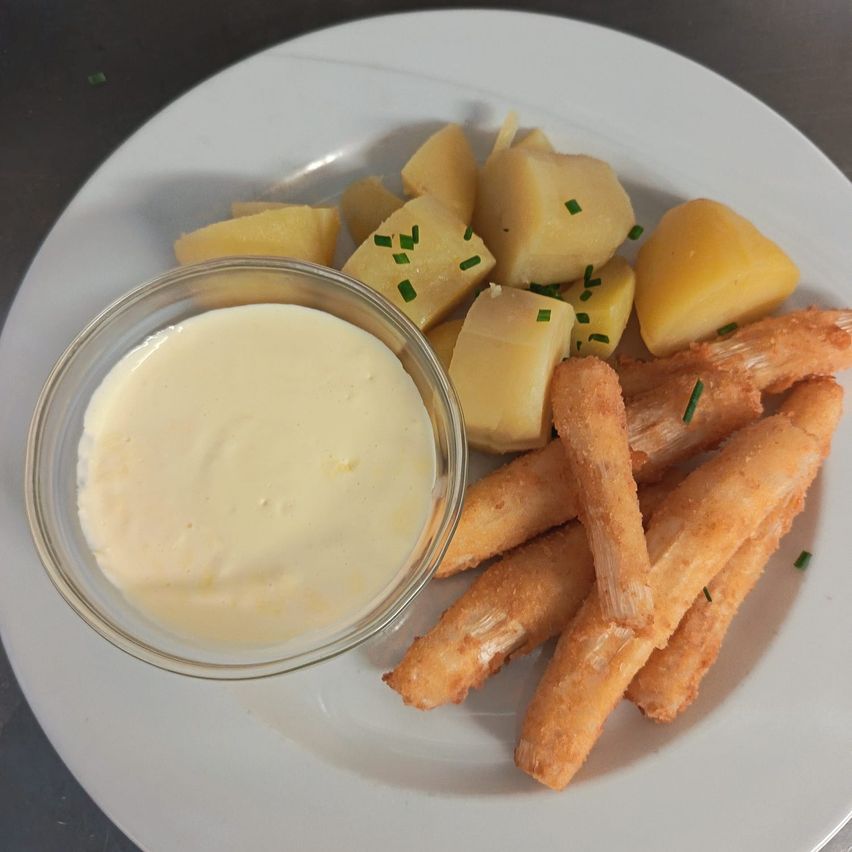 A plate with fried potatoes and fries. A creamy dip accompanies the dish.