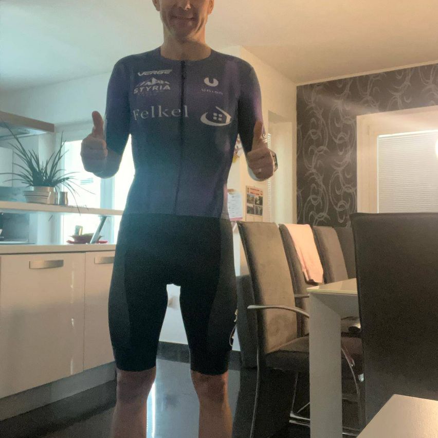 Ein Mann posiert in einer Küche und trägt ein Radtrikot mit dem Wort Felkel darauf.