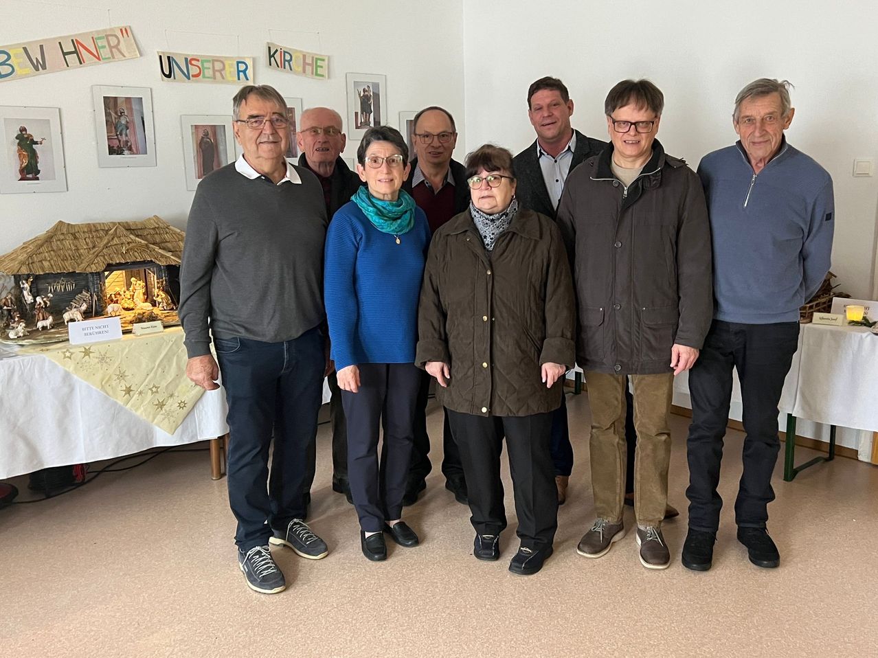 Eine Gruppe älterer Erwachsener, alle in Winterkleidung, posiert für ein Foto in einem Raum mit Weihnachtsdekoration.