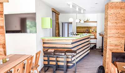 Ein moderner Essbereich mit Holzmöbeln, einer großen Theke und einem an der Wand montierten Fernseher. Die Theke hat eine grüne Oberseite und es gibt Geweihe und andere Dekorationen an der Wand.