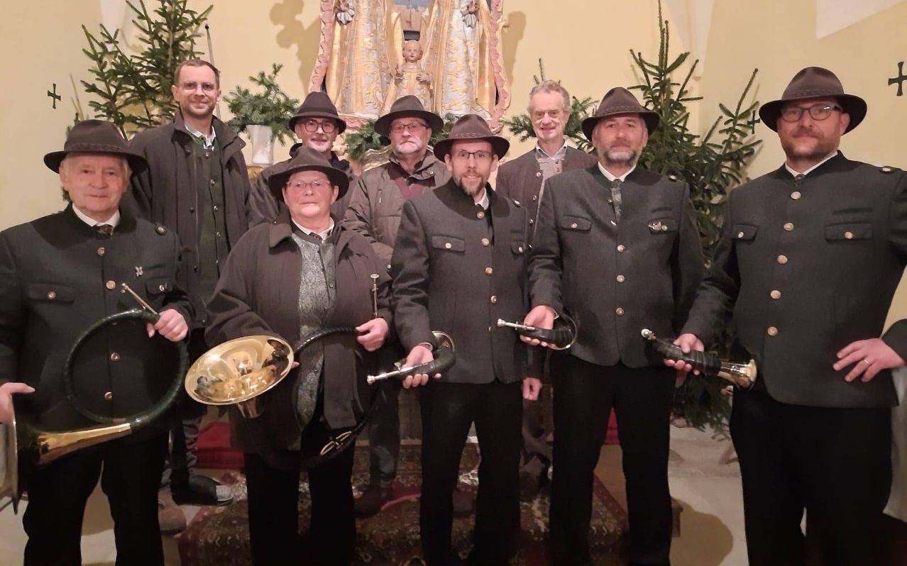 A group of men in hats and coats are posing for a photo with brass instruments in a church.
