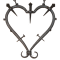 Eine herzförmige Metallstruktur mit Stacheln und einem Kreuz in der Mitte, die an Haken auf schwarzem Hintergrund hängt.