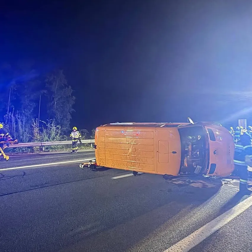 Ein Van ist auf der Straße nachts auf der Seite umgekippt. Rettungskräfte kümmern sich um die Szene.