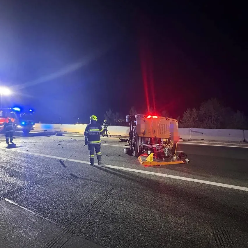 Ein Feuerwehrmann geht an einem umgestürzten Fahrzeug auf einer Autobahn in der Nacht vorbei.