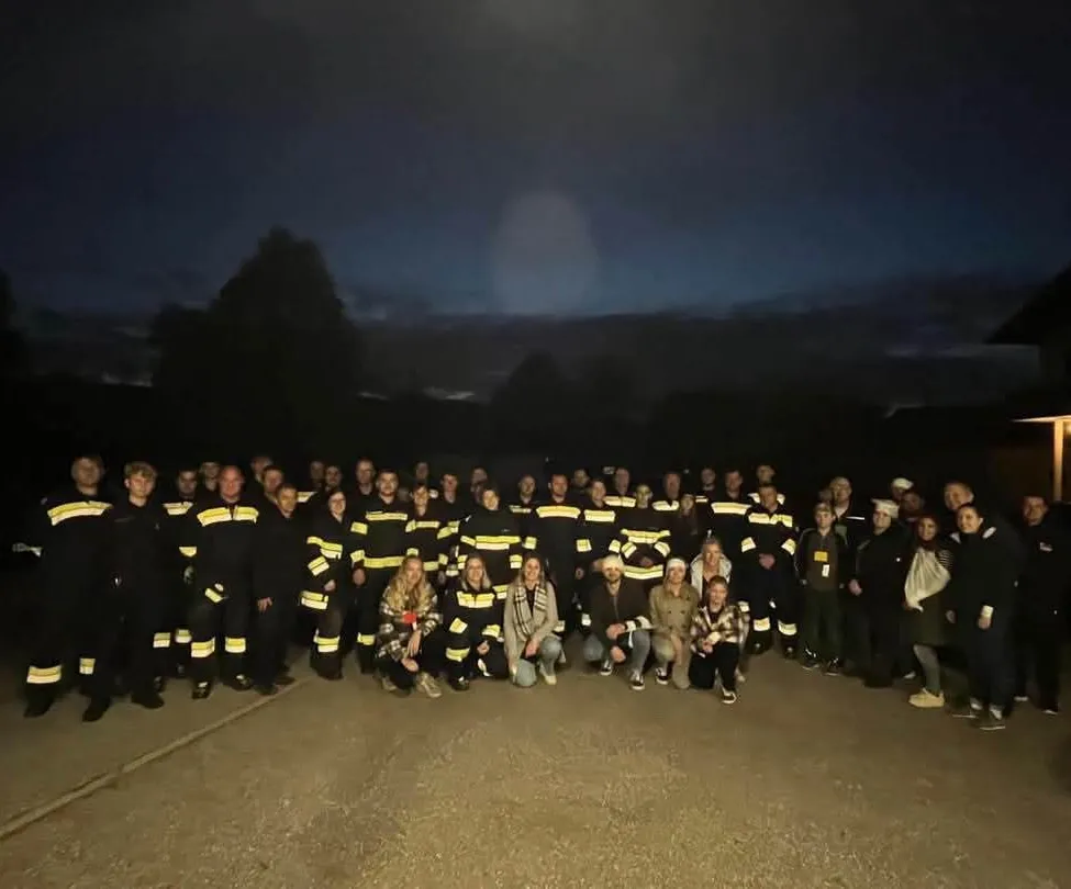 Eine Gruppe von Feuerwehrleuten und Freiwilligen posiert nachts für ein Foto.