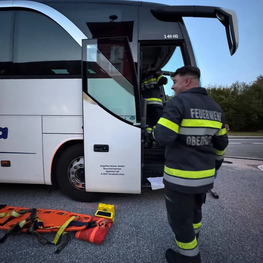 Ein Feuerwehrmann in Uniform verlässt einen Bus mit offener Tür. Ein weiterer Feuerwehrmann steht auf den Stufen des Busses.