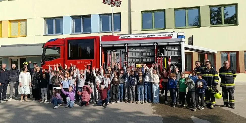 Eine Gruppe von Kindern und Erwachsenen posiert für ein Foto vor einem roten Feuerwehrauto.