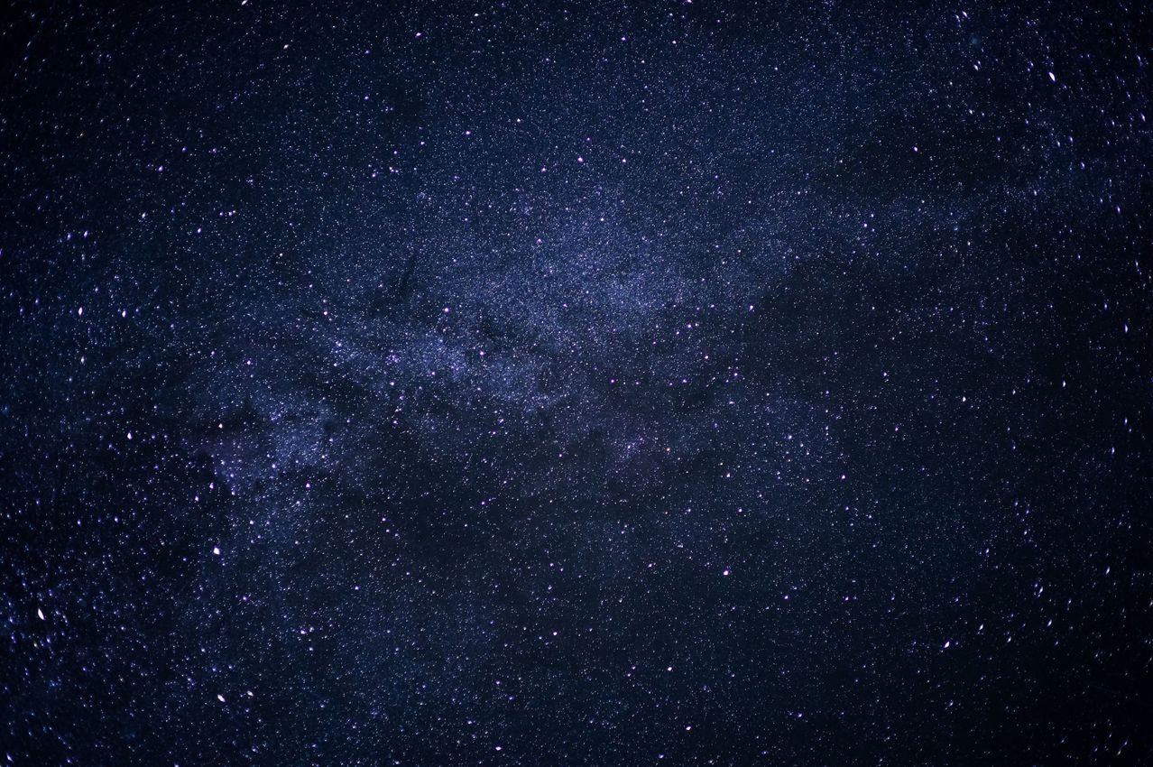 Ein Nachthimmel voller Sterne und der Milchstraße, die sich über den Himmel erstreckt. Die Sterne sind hell und der Himmel ist dunkel.