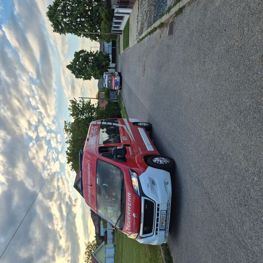 An aerial view of a red emergency vehicle parked on the side of a road, with houses and trees in the background.