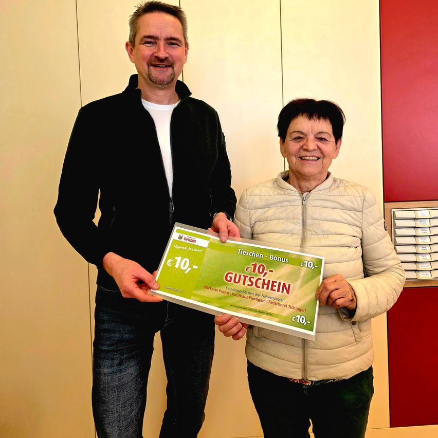 Ein Mann und eine Frau halten einen grünen Gutschein im Wert von 10 Euro und posieren lächelnd für ein Foto.