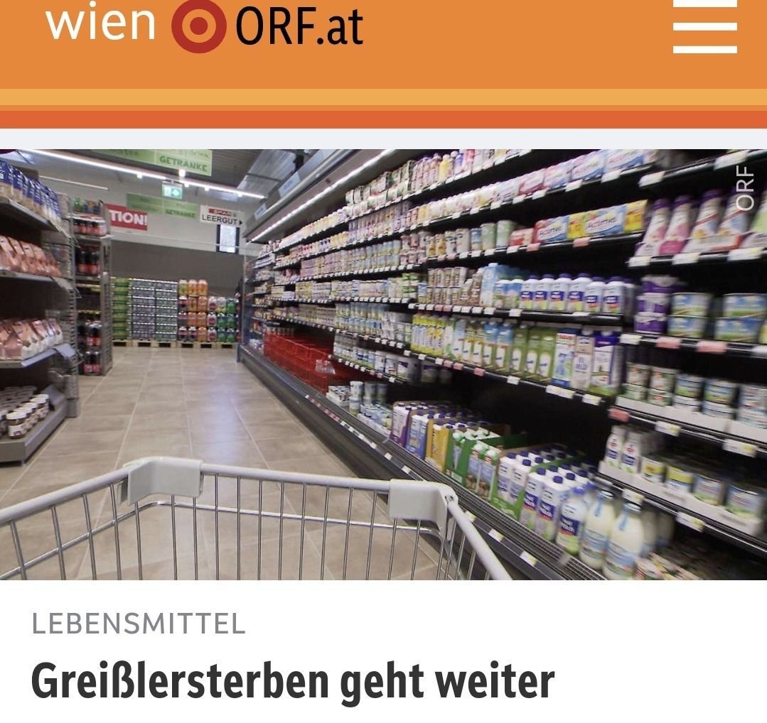 Ein Bild eines Supermarktgangs mit verschiedenen Produkten auf den Regalen. Der obere Teil des Bildes zeigt den Text 'Lebensmittel' und 'GreibLersterben geht weiter'. Ein Einkaufswagen steht im Vordergrund.