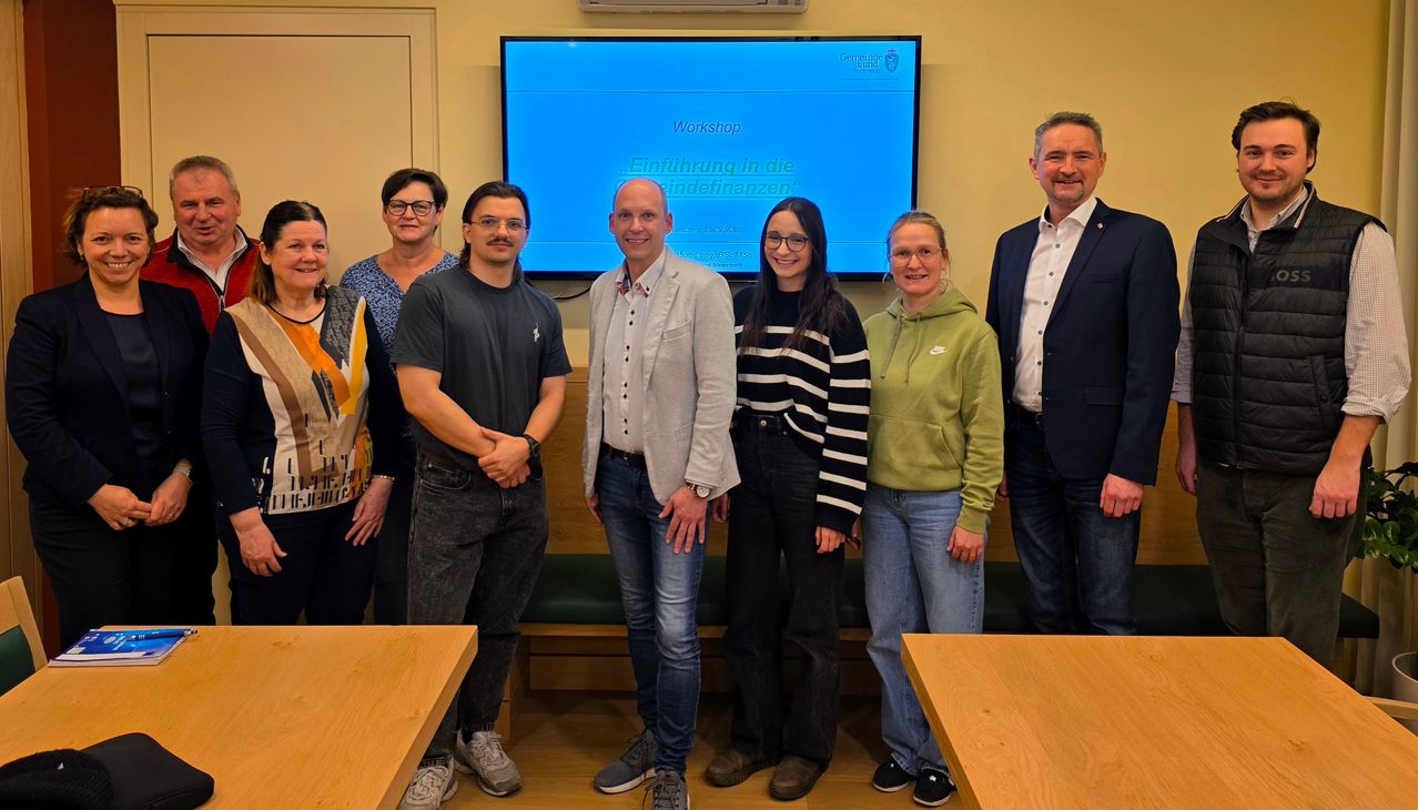 Eine Gruppe von Menschen steht vor einem Bildschirm mit dem Titel 'Workshop'. Sie scheinen an einem Workshop teilzunehmen.