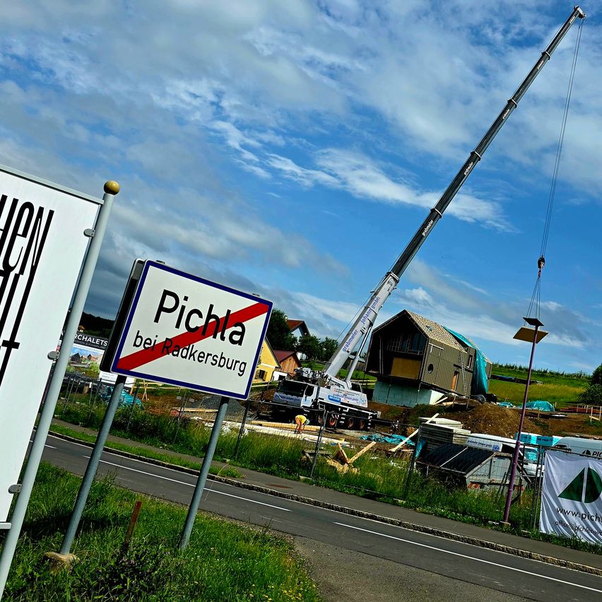 Ein Straßenschild für Pichla bei Radkersburg. Ein Haus wird gebaut und ein Kran ist im Einsatz.