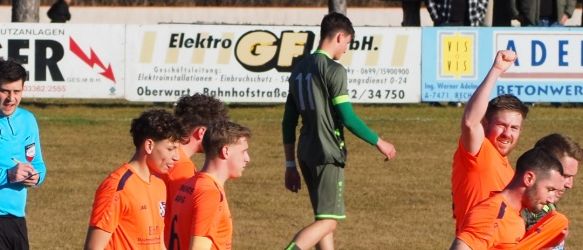 A soccer team in orange uniforms celebrates a goal on a field with a referee. The players are walking and looking at the referee.