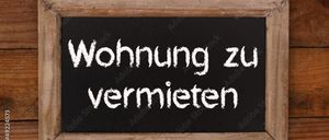 Ein Holzrahmen mit einer Tafel, auf der 'Wohnung zu vermieten' steht, an einer Holzwand, mit einem Seil, das von oben hängt.