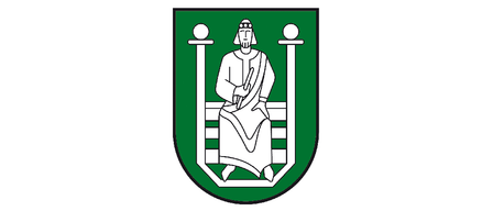 Ein Mann in traditioneller Kleidung sitzt mit einem Buch auf einer Bank, eingerahmt von einem grünen Schild.