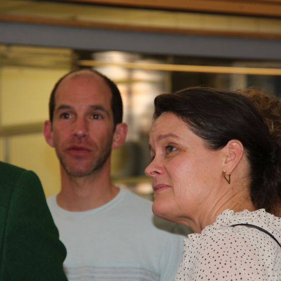 Ein Mann und eine Frau stehen zusammen und blicken nach vorne, möglicherweise bei einer Veranstaltung.